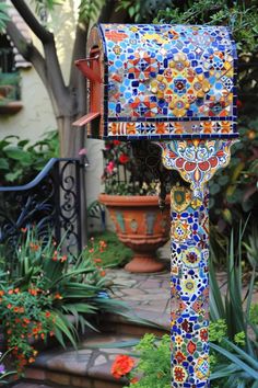 a colorful mailbox sitting in the middle of a garden