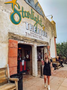 a woman walking in front of a theatre on the side of a building that says starlight theatre