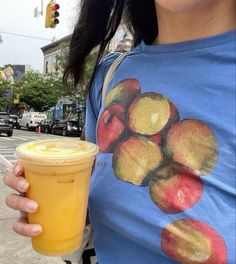 a woman is holding a cup of juice on the street