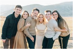 a group of people standing next to each other in front of a mountain with mountains behind them