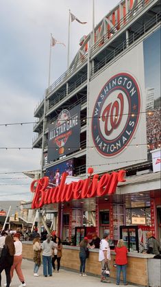 people are standing in front of the ballpark at nationals stadium, where there is a sign that says washington nationals