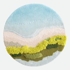 a circular painting with grass and mountains in the background, on a white circle surface