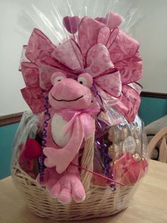 a pink stuffed animal sitting in a basket filled with chocolates and candy bar wrappers