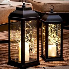 two black lanterns with lit candles on the floor