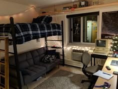 a dorm room with bunk beds, desk and computer on the floor in front of a christmas tree