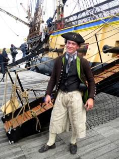 a man standing on top of a wooden dock next to a boat