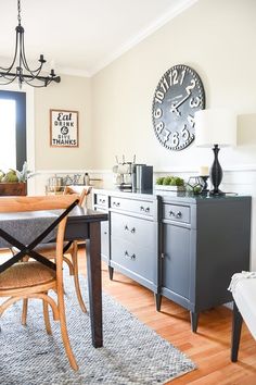 a dining room table with chairs and a clock on the wall