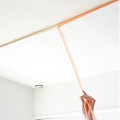 a woman is hanging from the ceiling with an orange string in her hand and she is holding something up above her head