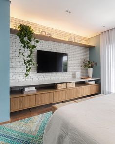 a bedroom with a bed, television and plants on the shelves in front of it