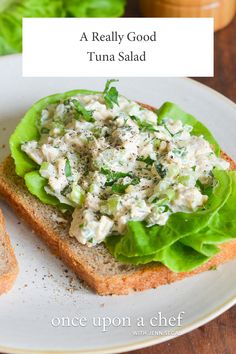 a sandwich with lettuce and chicken salad on it sitting on a white plate