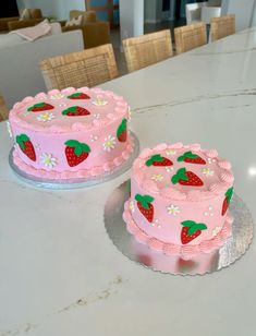 two pink cakes sitting on top of a table next to each other with strawberries on them