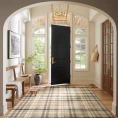 an archway leading to a living room with a rug on the floor and a black door