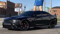 a black sports car parked in front of a tall woman statue on top of it