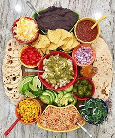 a platter filled with different types of food and condiments on it, including tortillas