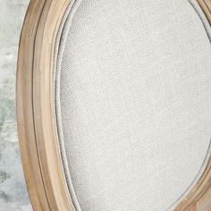 an oval wooden frame with white upholstered fabric