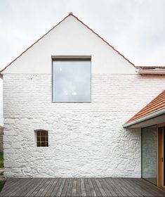 a white brick building with a wooden deck and large open window on the side of it