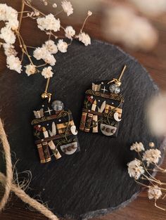 the earrings are made out of metal and decorated with gold, black and white designs