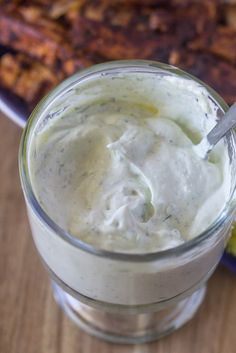 a spoon in a glass with some food on the side