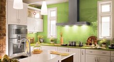 a kitchen with green walls and white cabinets is pictured in this image, there are pears on the counter