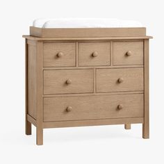 a baby's dresser with drawers and a white blanket on top, against a white background