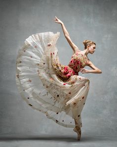 a woman in a white dress is dancing with her arms spread out to the side