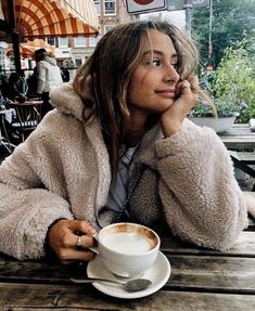 a woman sitting at a table with a cup of coffee