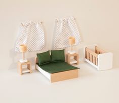 a dollhouse bedroom with green bedding and white furniture, including a crib