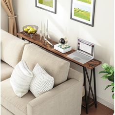 a laptop computer sitting on top of a wooden table next to a white couch in a living room