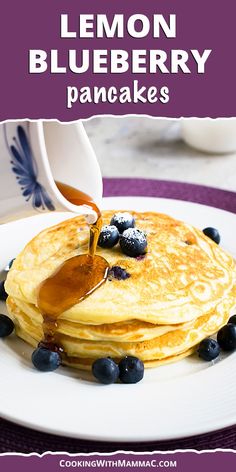 a stack of pancakes with syrup being drizzled over them and blueberries on the side