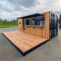 a large container sitting on top of a parking lot next to a wooden platform with an open door