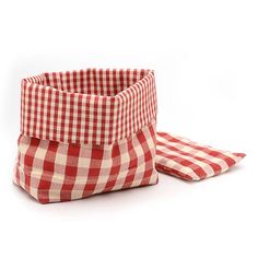 a red and white checkered basket sitting next to a pair of cloth napkins