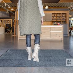 a woman walking across a kitchen floor wearing boots