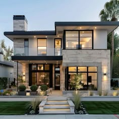 a modern house with stairs leading to the front door and large windows on each side