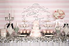 a table topped with lots of cakes and desserts next to a pink striped wall