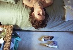 a man laying on top of a bed next to a wicker basket filled with items