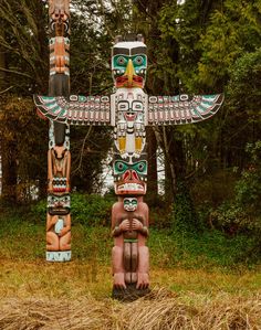 two totemas in the grass with trees in the background