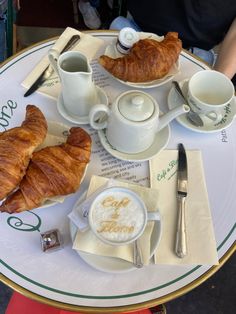 a table with coffee, croissants and other breakfast foods on top of it