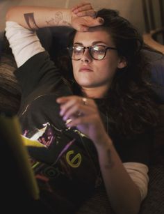 a woman with glasses is laying on the couch