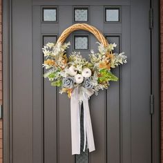 a wreath on the front door of a house decorated with flowers and greenery,