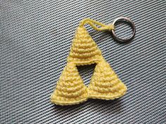 a crocheted triangle shaped keychain sitting on top of a metal surface