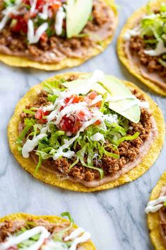 several tacos with meat, lettuce and cheese on them sitting on a table