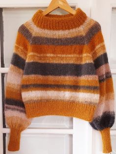 an orange and black striped sweater hanging on a door