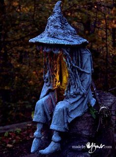 a scarecrow statue sitting on top of a tree stump