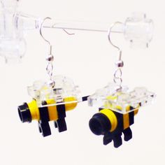 two yellow and black bee shaped earrings hanging from clear hooks on a white background,