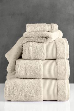 a stack of white towels stacked on top of each other in front of a gray wall