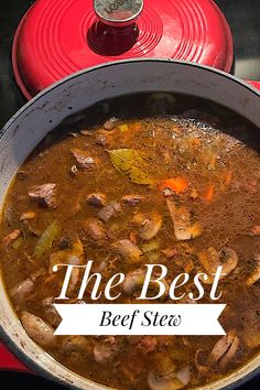 the best beef stew is in a pot with a red lid and spoon next to it