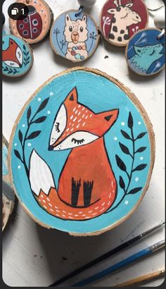 painted wooden slices with animals on them sitting next to paintbrushes and paintsticks