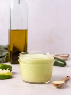 a glass jar filled with green liquid next to sliced jalapenos