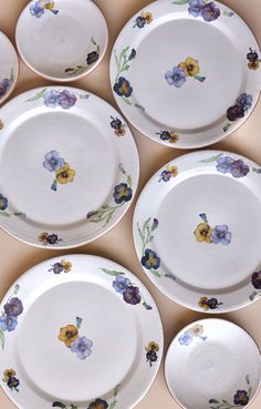 six white plates with flowers painted on them