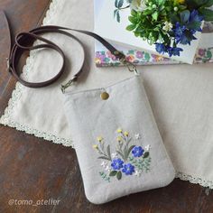 a small purse sitting on top of a table next to a bouquet of blue flowers